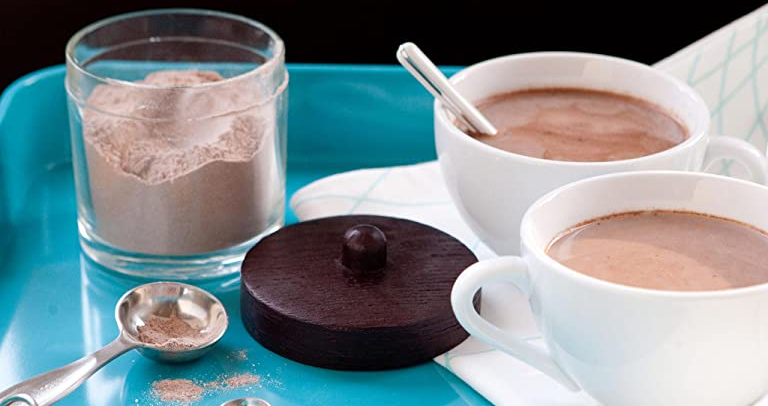 ingredients for hot chocolate set up in a blue tray including mugs with hot chocolate