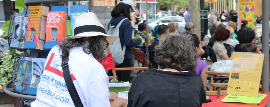 An Information Ambassador points out directions on a map to a visitor in Richard Tucker Park