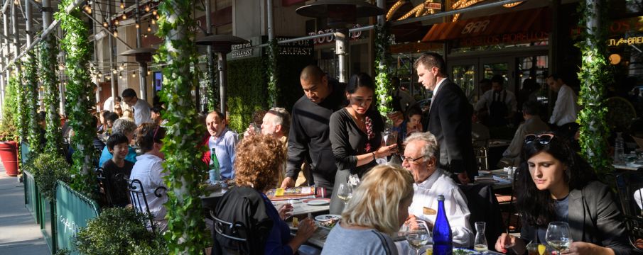 People dine in an outdoor seating area on Broadway in the summertime 