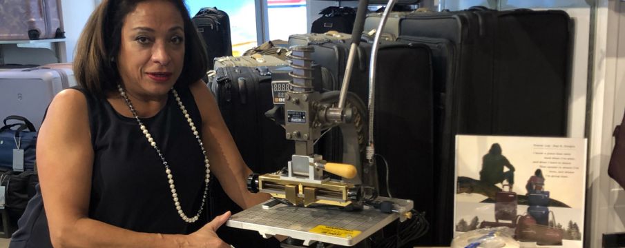 Store manager at Innovation Luggage poses with engraving machine in store