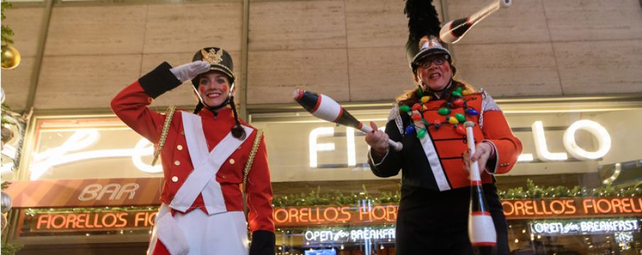 two stilt walkers dressed as soldiers pose for a photo on the street during Winter's Eve