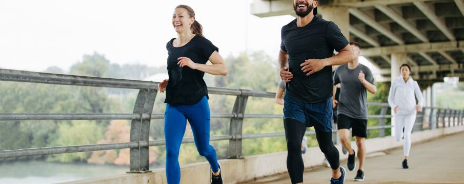 runners cross a pedestrian bridge in a park