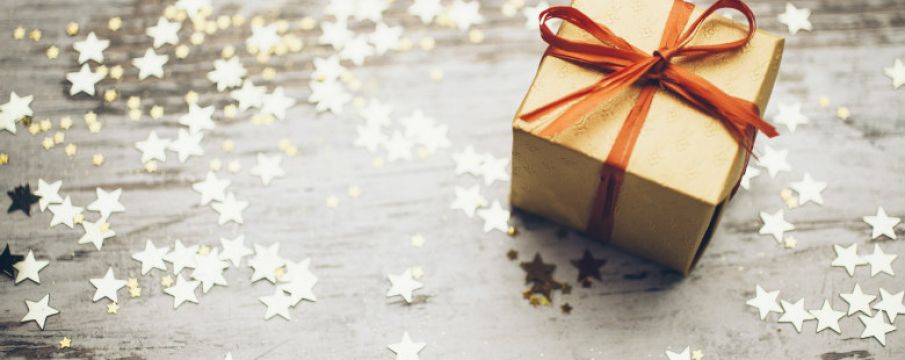 brown paper wrapped gift box with a red ribbon on a table surrounded by cutout stars