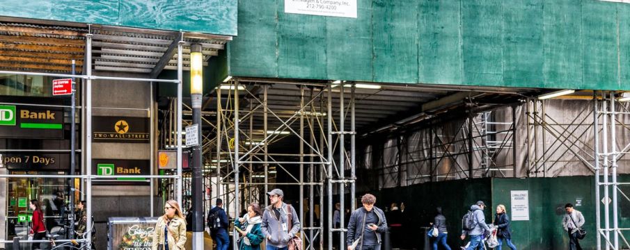 a sidewalk shed stands around a construction site downtown