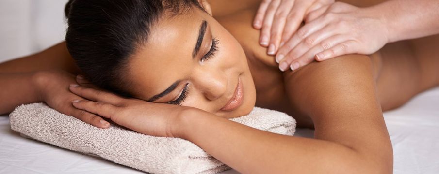 a woman receives a shoulder massage while lying down on a massage table at Upper West Spa