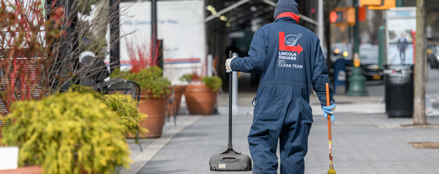 a clean team member walks along the sidewalk of Richard Tucker Park in March 2020