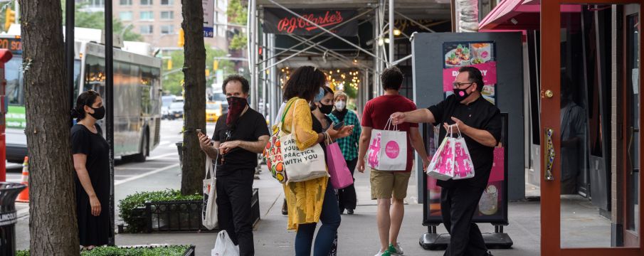 people wait outside for take-out at Rosa while one employee hands a bag to a customer