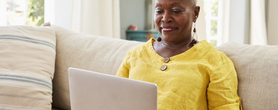 an older woman uses her laptop on her living room couch