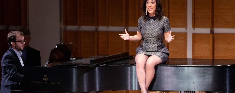 Gabrielle Stravelli sitting on a piano and singing