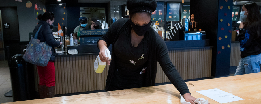 a worker inside of the Starbucks at 63rd St and Broadway wipes down a counter top for patrons with disinfectant 