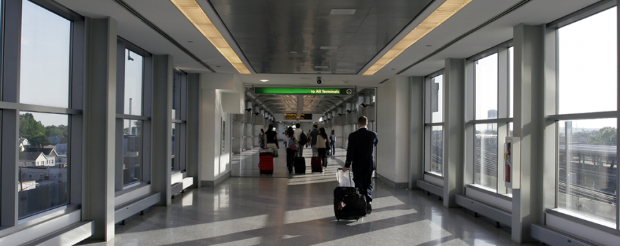 people walking down the pedestrian overpass with luggage at JFK Airport