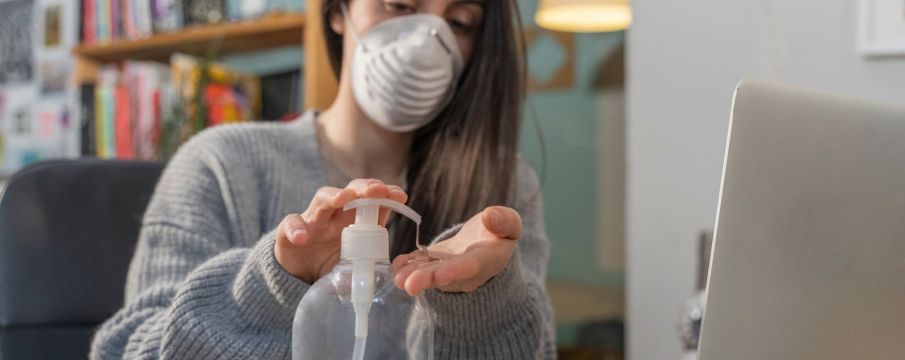 woman with a mask using hand sanitizer