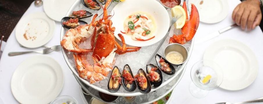 seafood spread on a table with hands reaching across to grab plates