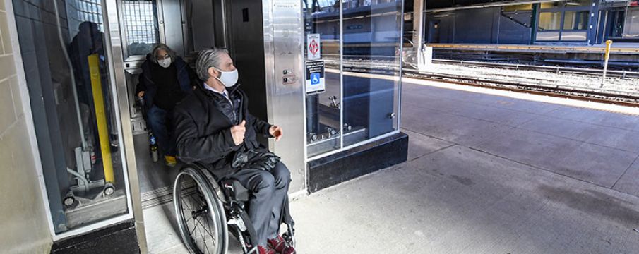 man in wheel chair entering train station